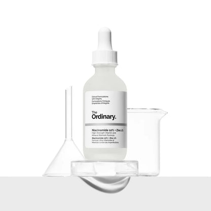 A 30ml bottle of The Ordinary Niacinamide 10% + Zinc 1% is displayed against a white background, ideal for blemish-prone skin. It accompanies a clear funnel and beaker on a clean surface, highlighting the serums niacinamide and zinc PCA benefits.