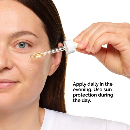 A person with light skin and dark hair, wearing a white top, uses a dropper to apply The Ordinary Retinol 1% In Squalane 30ml to their face. Text reads: Apply daily in the evening. Use sun protection during the day.