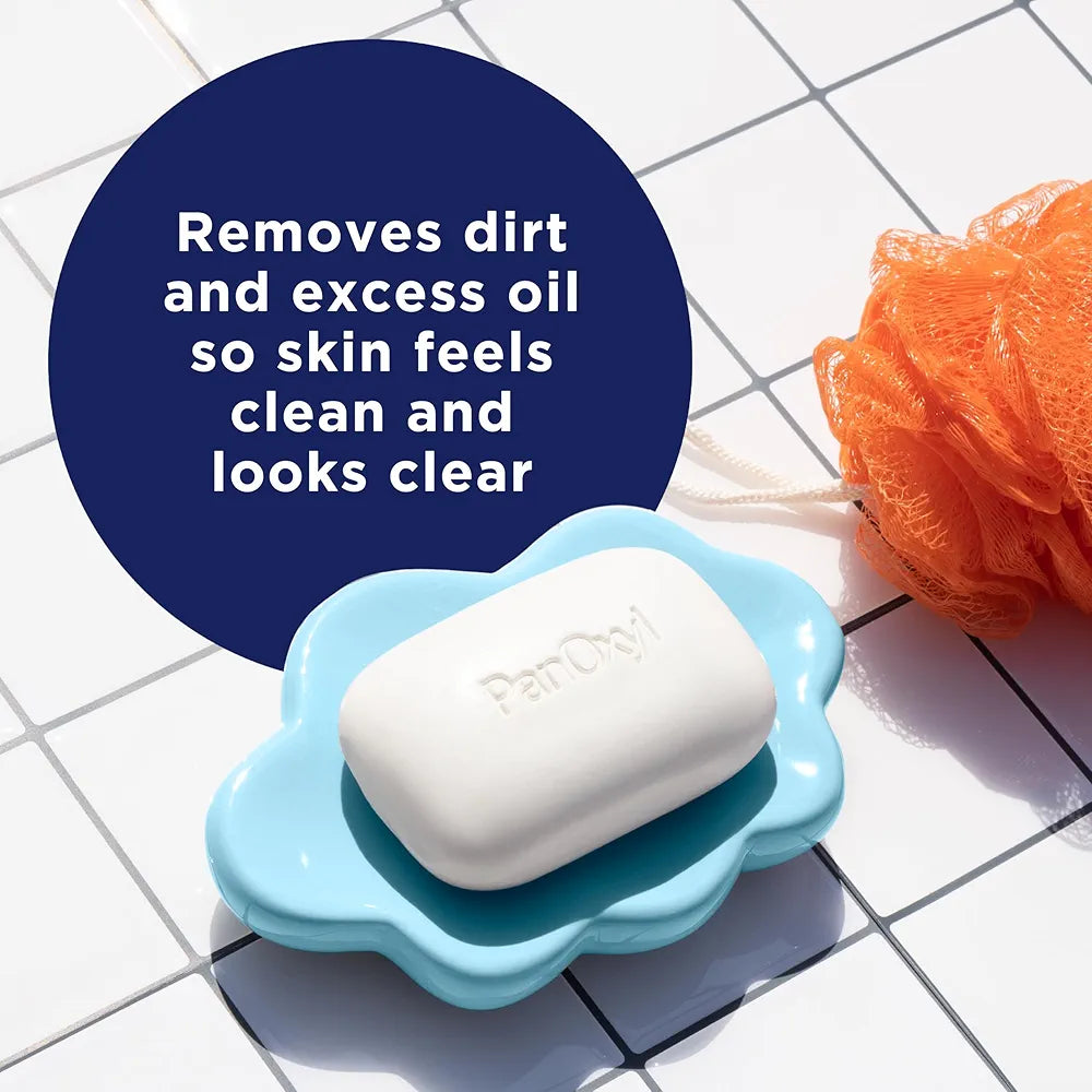 Bar of soap in a blue dish with a loofah on a tiled surface, featuring text about skin care.