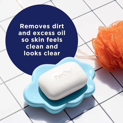 Bar of soap in a blue dish with a loofah on a tiled surface, featuring text about skin care.