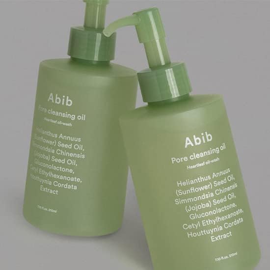 Two matte green Abib Pore Cleansing Oil Heartleaf Oil-Wash bottles, each 200ml, feature pump dispensers and labels highlighting ingredients like sunflower oil, jojoba seed oil, and houttuynia cordata extract. The white text contrasts with the green surface for a deep cleansing routine.