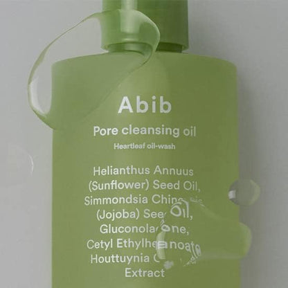 A green bottle of Abib Pore Cleansing Oil Heartleaf Oil-Wash 200ml shines with water droplets. This cleanser, by Abib, deeply cleans pores with ingredients like Sunflower Seed Oil, Jojoba Seed Oil, and Houttuynia Cordata Extract.