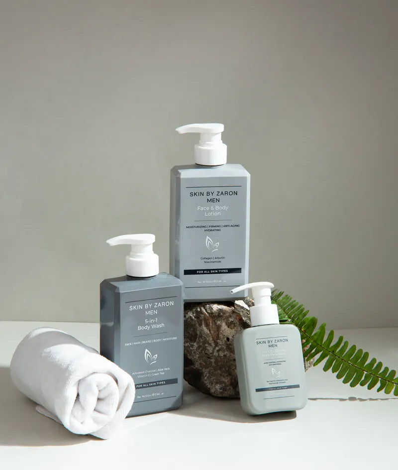 Three bottles of 'Skin by Zaron' products on a neutral background with a towel and leaf.