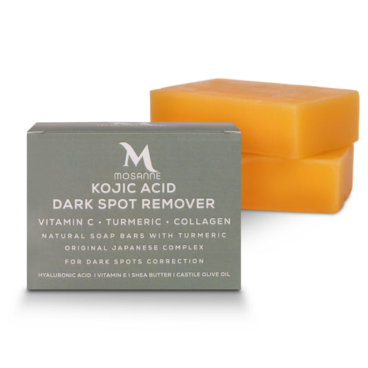A box labeled MOSANNE Kojic Acid Dark Spot Remover Soap - 2 pack is in the foreground, featuring skin-brightening ingredients like Vitamin C and turmeric. Behind it, two orange soap bars are stacked, enhancing this dark spot correctors powerful formula.