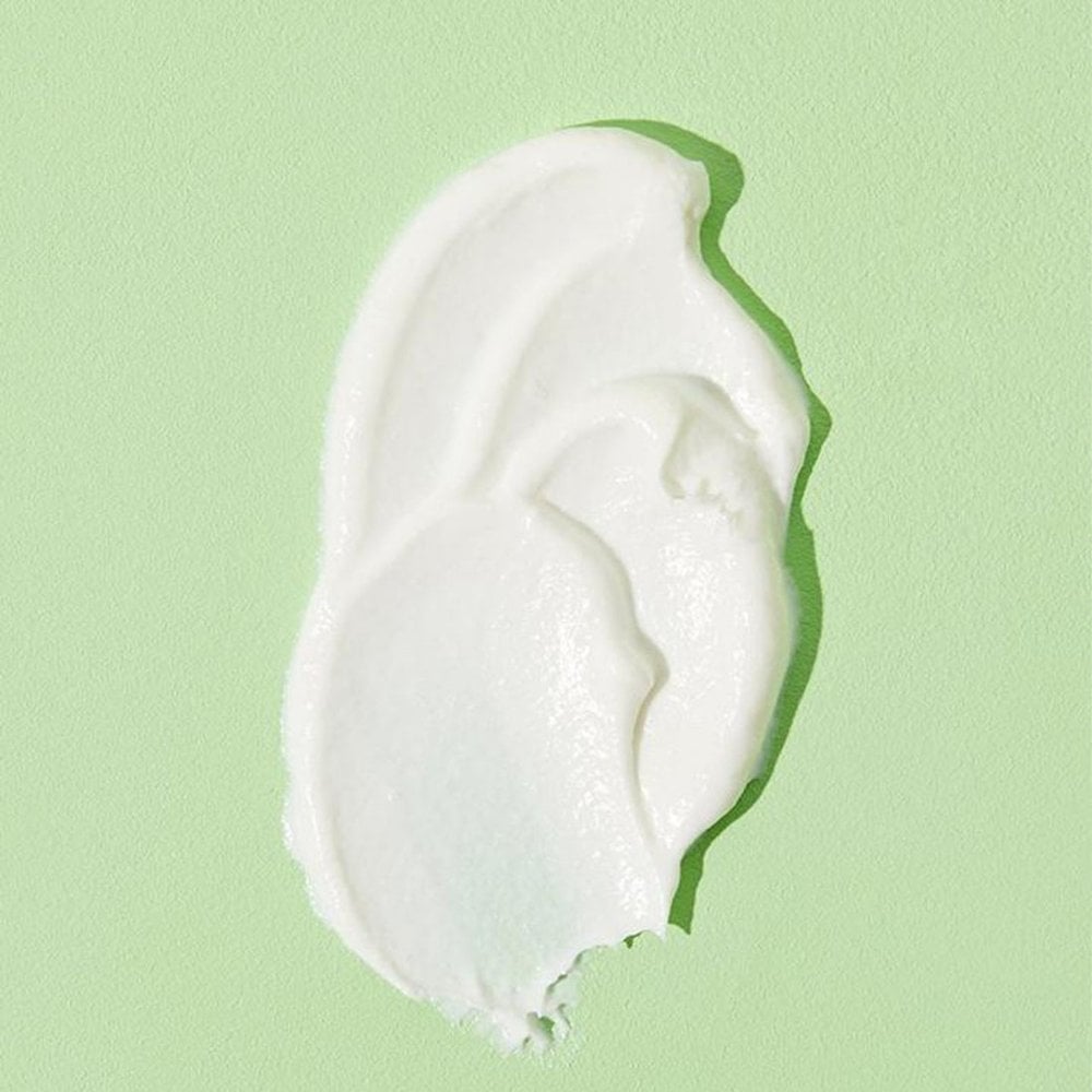 A dollop of COSRX Centella Blemish Cream rests on a light green surface, highlighting its smooth, creamy texture with visible peaks and ridges, ideal for treating acne scars.