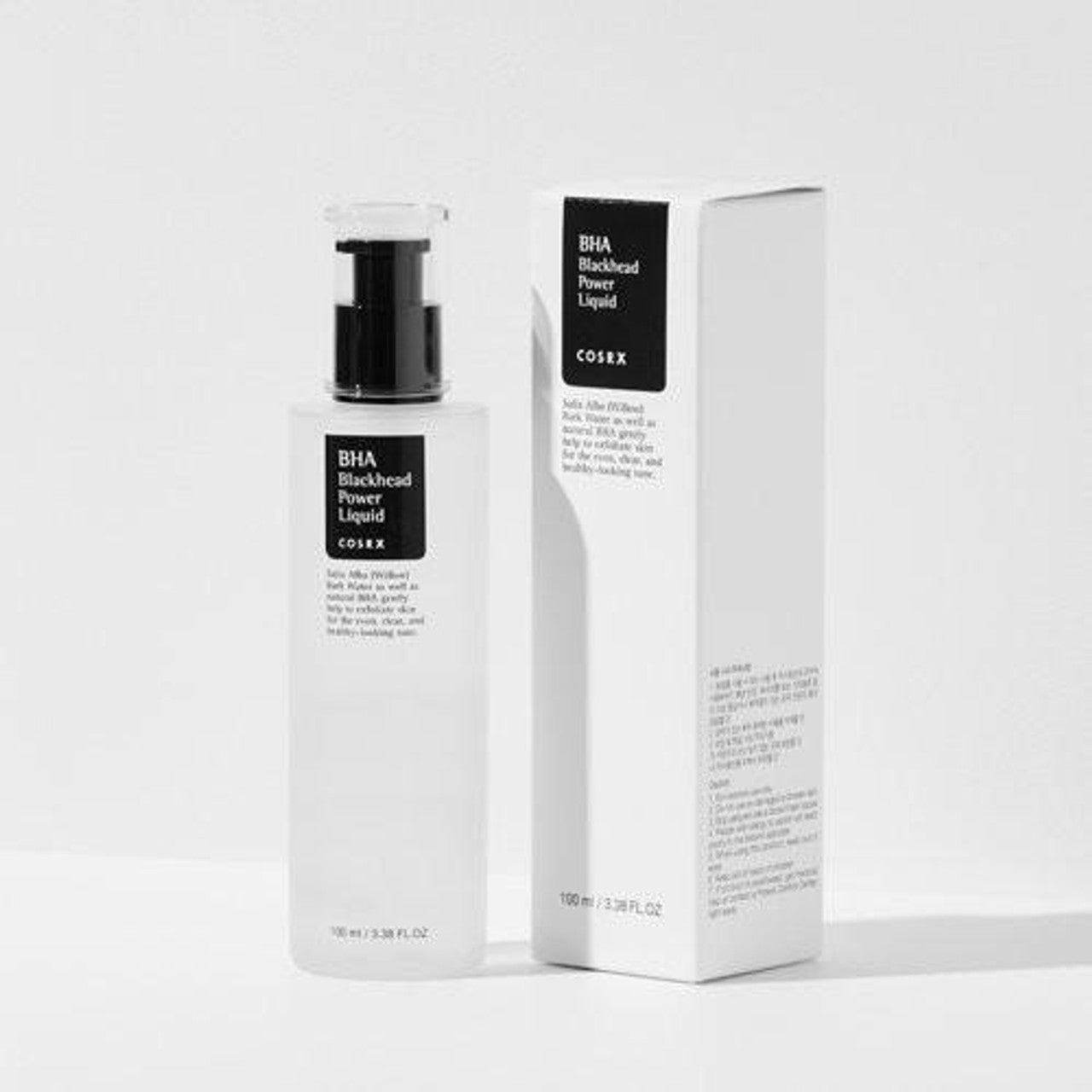 A bottle and box of COSRX BHA Blackhead Power Liquid 100ml stand against a plain backdrop. The transparent bottle with black pump and monochrome label reflects the boxs sleek design, effectively exfoliating dead skin cells for smooth, clear skin using natural ingredients.