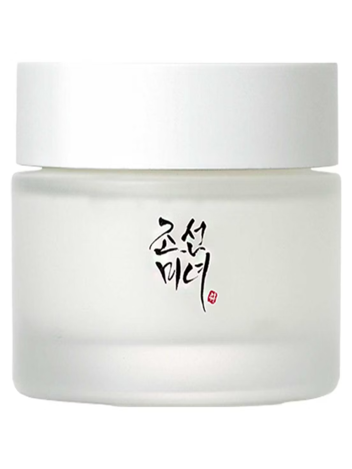 A 50ml Beauty of Joseon Dynasty Cream jar, featuring a white lid and black Korean calligraphy, likely contains a skincare product promising dewy skin.