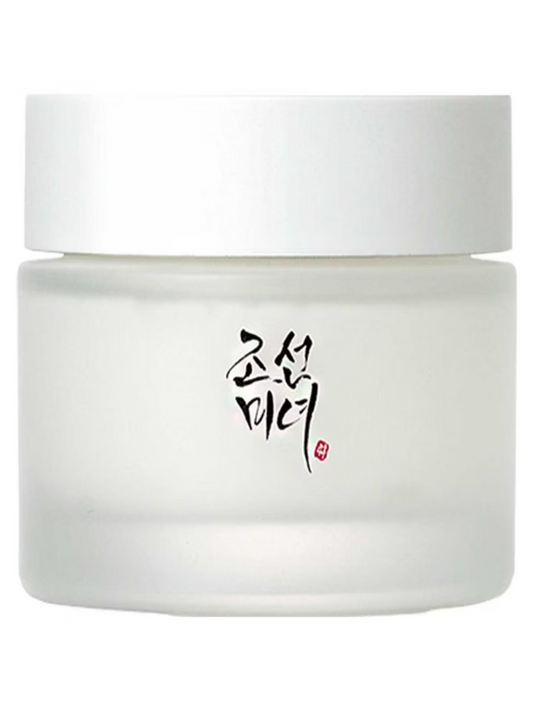A 50ml Beauty of Joseon Dynasty Cream jar, featuring a white lid and black Korean calligraphy, likely contains a skincare product promising dewy skin.