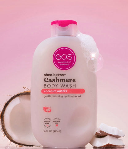 EOS Cashmere Body Wash bottle with coconut pieces on a pink background