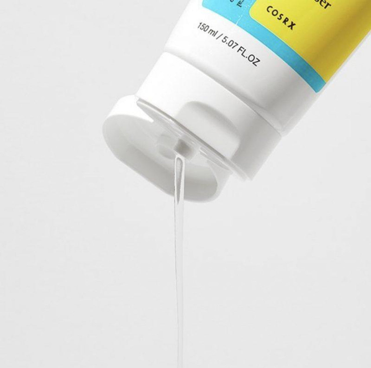 The COSRX Low PH Good Morning Gel Cleanser, in a white tube with a yellow label and blue text, dispenses clear gel. Marked 150 ml / 5.07 fl. oz., the vegan, cruelty-free cleanser forms a thin stream from its open cap for gentle daily care.