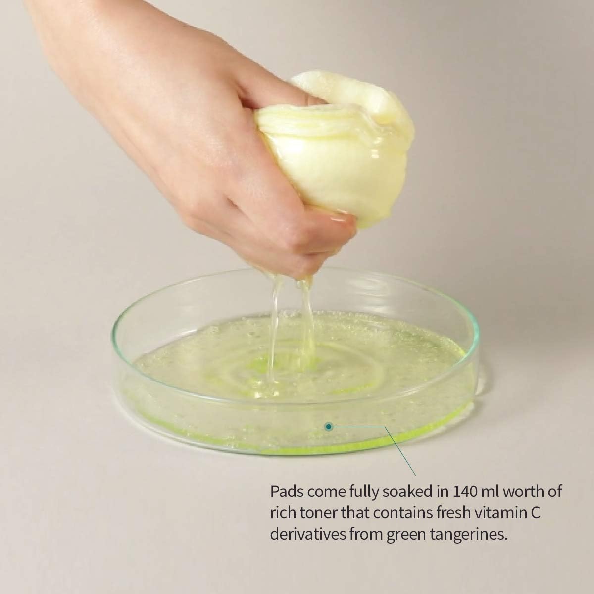 A hand squeezes a Goodal Green Tangerine Vita C Toner Pad over a dish, releasing clear liquid into a greenish-yellow fluid. Text: Pads are fully soaked in 160ml of toner with vitamin C derivatives from green tangerines to combat dark spots and hyperpigmentation.