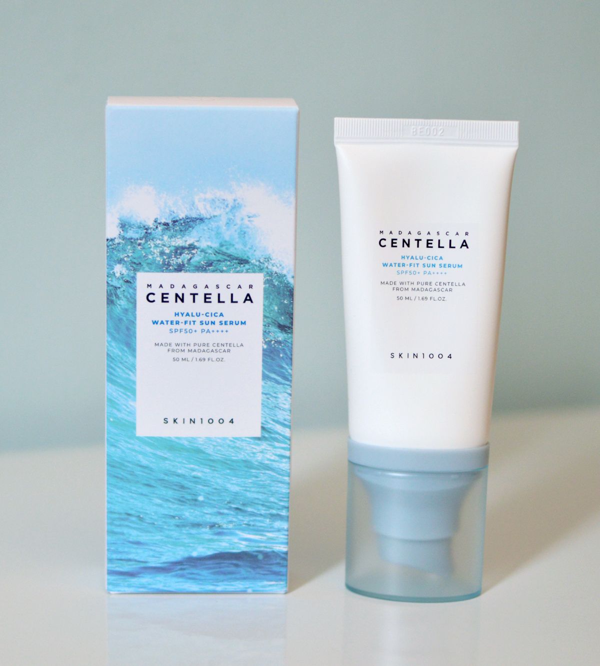 SKIN1004 Madagascar Centella Sun Serum beside its ocean-themed box, designed with SPF50+ PA++++ for UV protection and deep hydration with Hyaluronic Acid