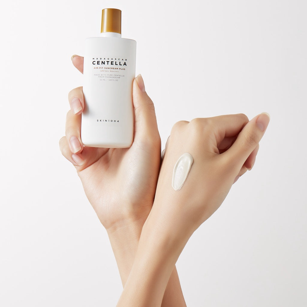 A hand holding SKIN1004 Air-Fit Suncream Plus with a swatch on the skin, showcasing its lightweight, non-greasy texture for UV protection