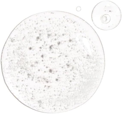 The Ordinary Alpha Arbutin 2% + HA Serum 30ml features clear gel droplets with small bubbles, highlighting its glossy texture on a white background. One large droplet and two smaller ones sit above, all infused with alpha arbutin to reduce hyperpigmentation while hydrating the skin.
