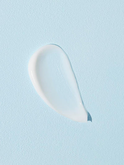 A dollop of COSRX Ultimate Nourishing Rice Overnight Spa Mask is applied on a smooth, light blue surface, creating an abstract shape. Infused with rice extract, its texture is smooth and glossy, softly reflecting light off its moisturizing surface.